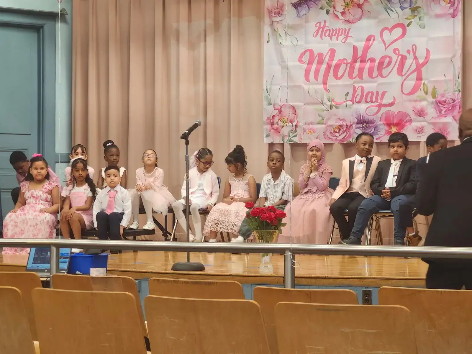 Students dressed in pink perform on stage at a school Mother's Day celebration