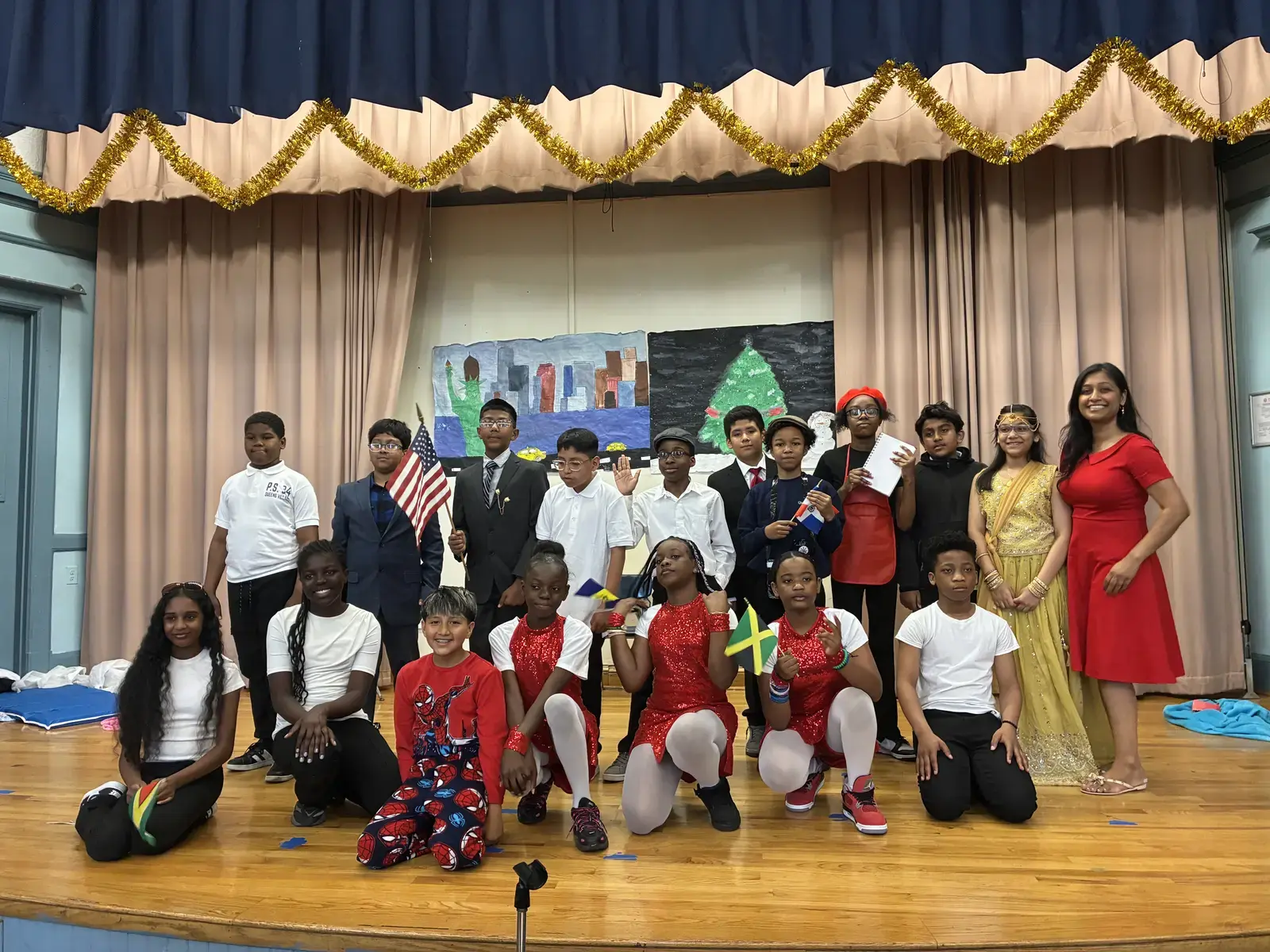 Students and teacher pose on stage holding international flags at school cultural celebration