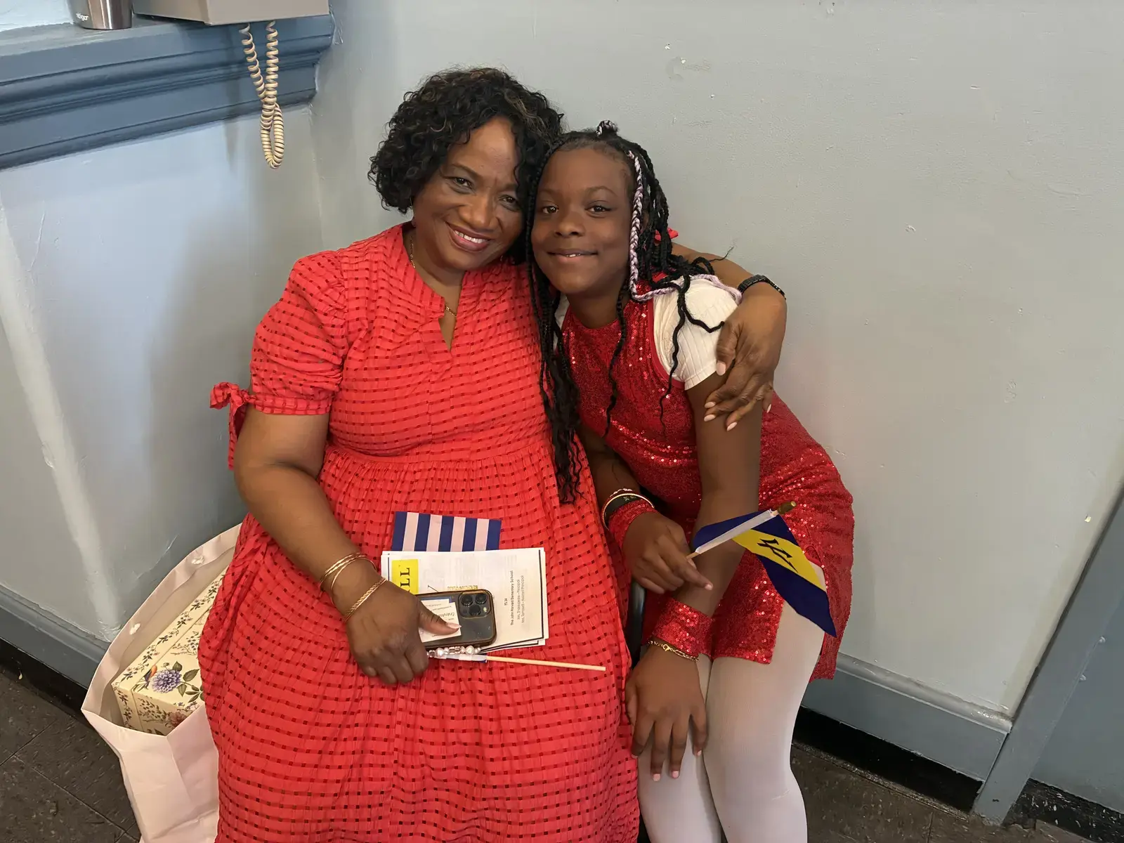 Student in red costume holds Barbados flag with adult supporter