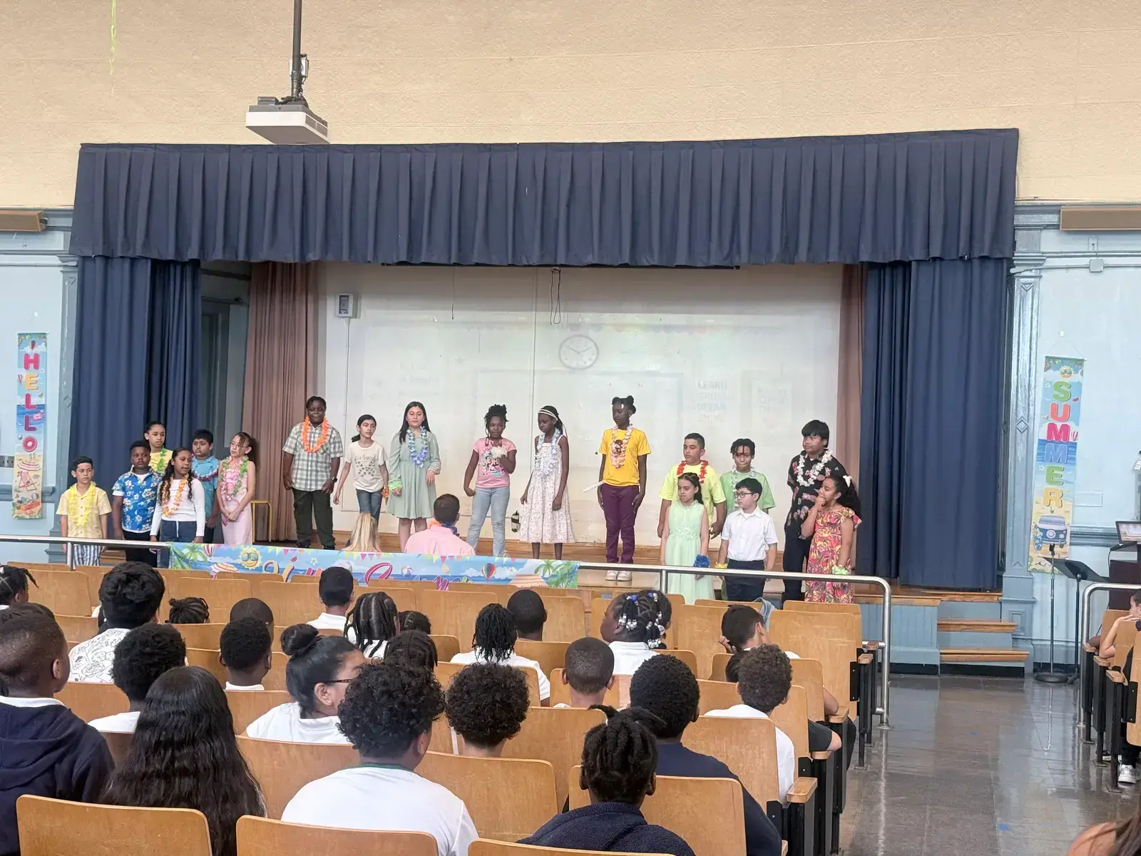 Students performing on stage during a summer school assembly