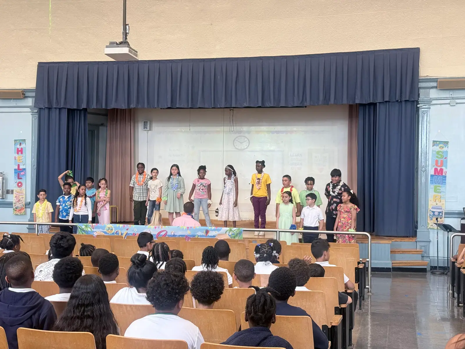 Students performing on auditorium stage during end-of-year school assembly