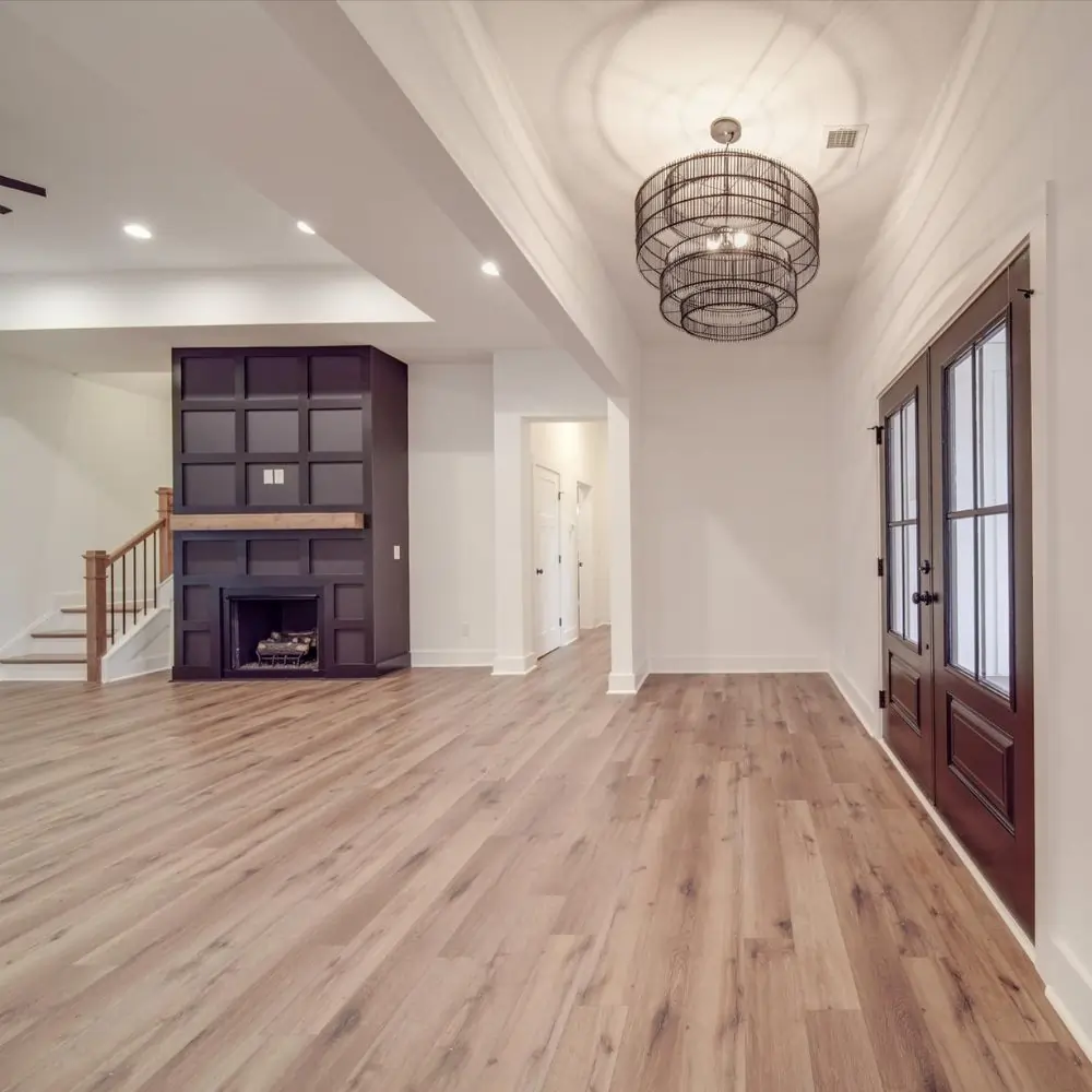 Open-concept entryway with custom lighting, hardwood floors, and modern black fireplace.