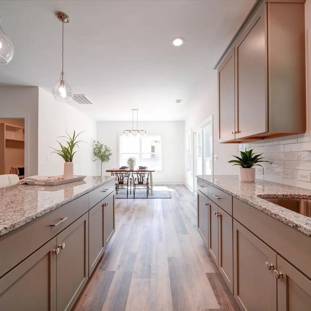 Modern kitchen with granite countertops, shaker cabinets, and open dining area with natural light.