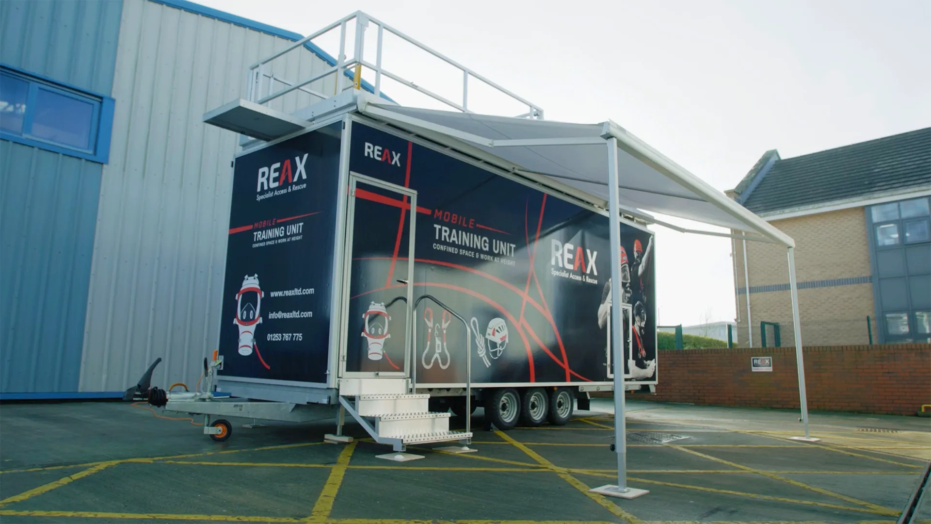 A large trailer with the words Confined space training unit on the side, with an awning