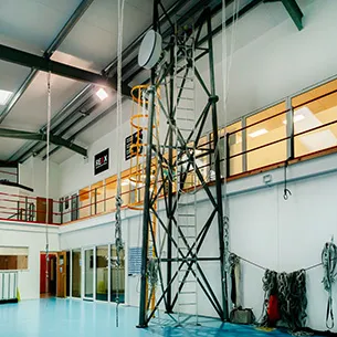 Telecoms tower inside a big building with ropes and a ladder to climb up the tower.