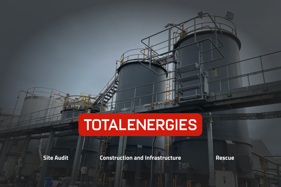 Silo tanks with a grey sky and the words TotalEnergies