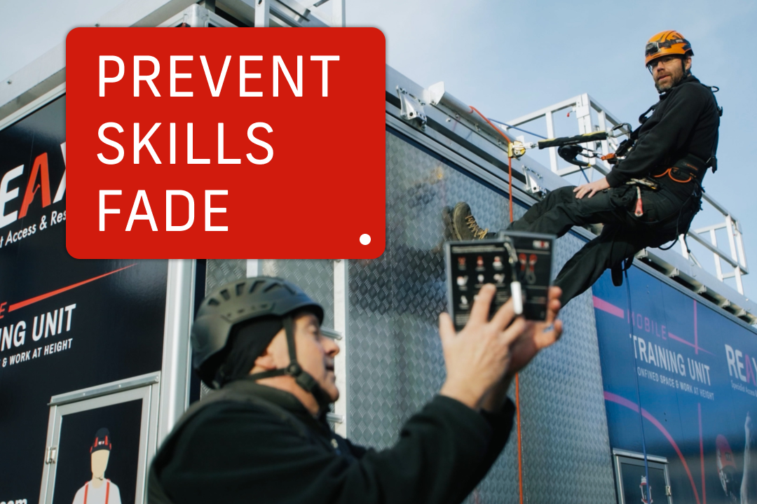 A man ascending a steel plated wall, with another man instructing with a booklet