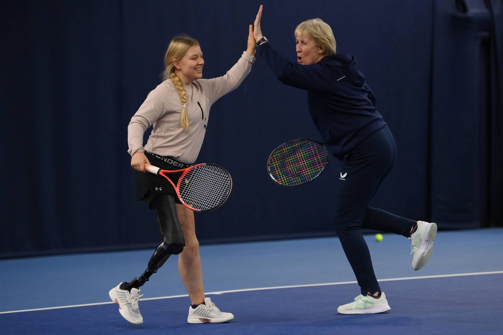 A player with a prosthetic leg high-fiving her coach on an indoor court