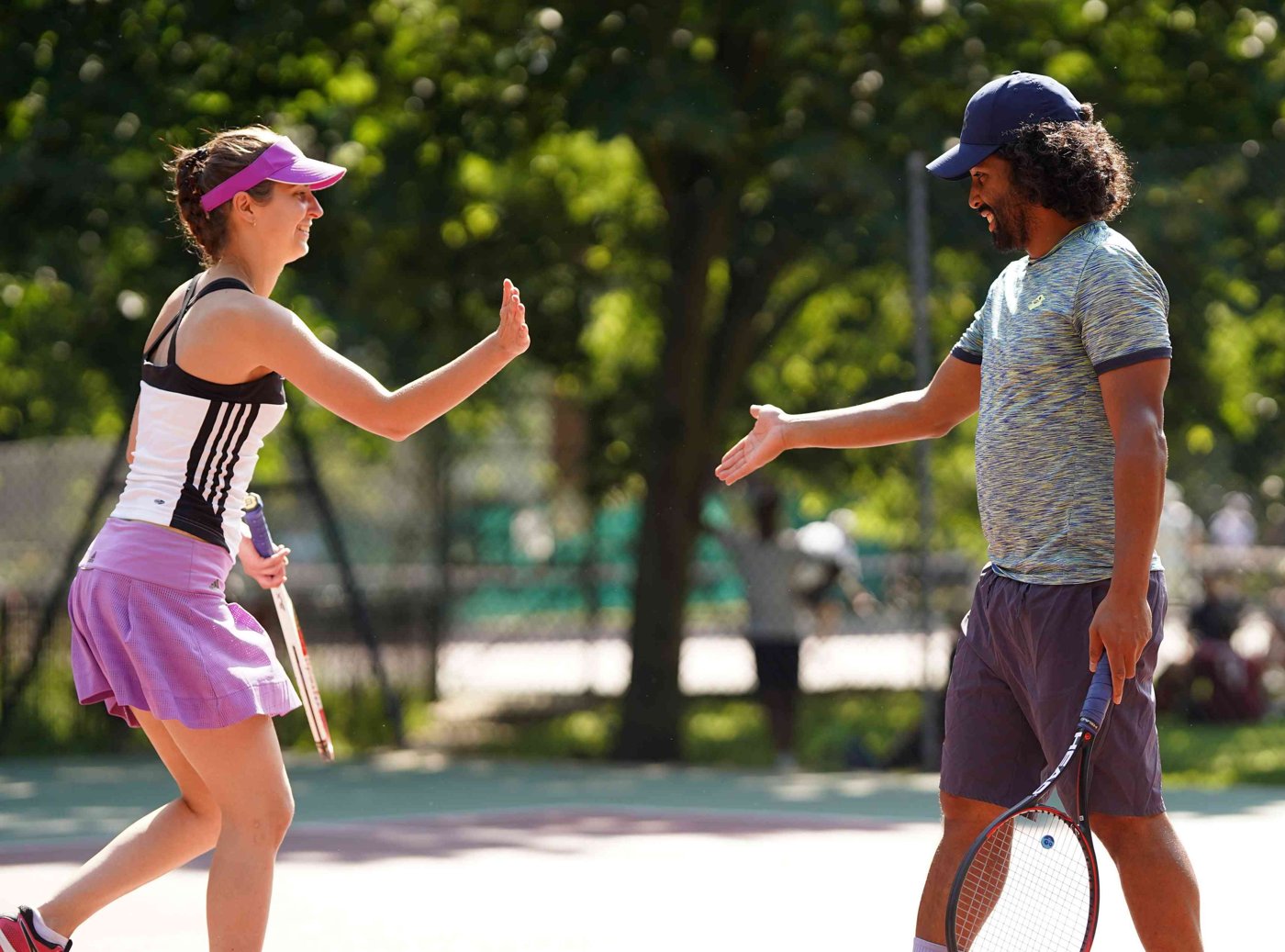 Two players high-fiving between points on a park court