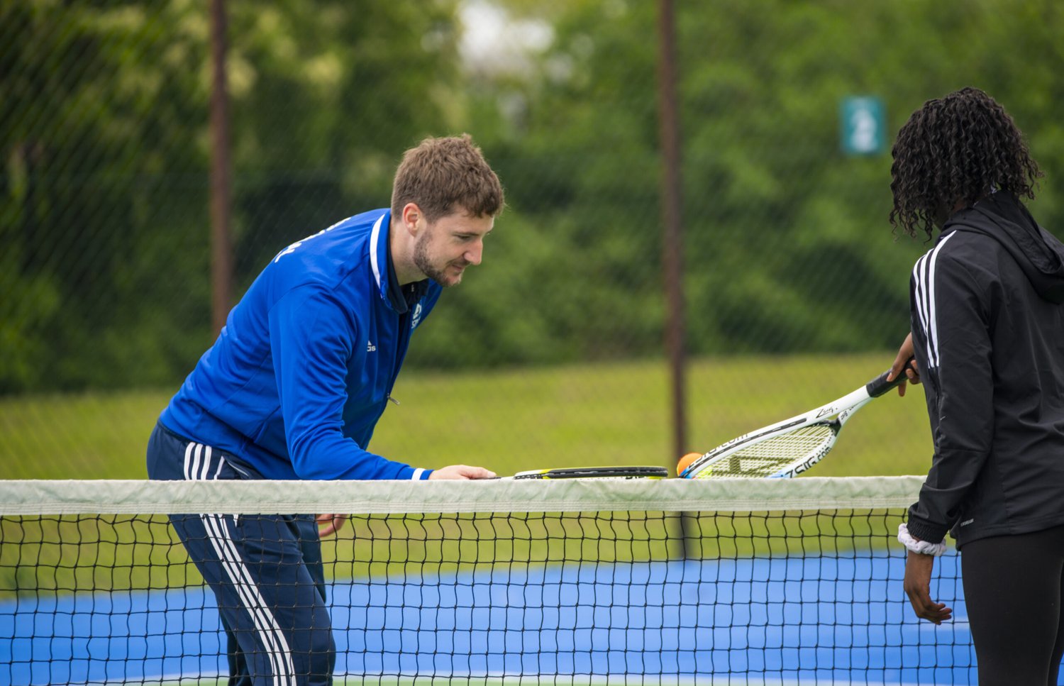 A National Tennis coach working one to one with a player at the net