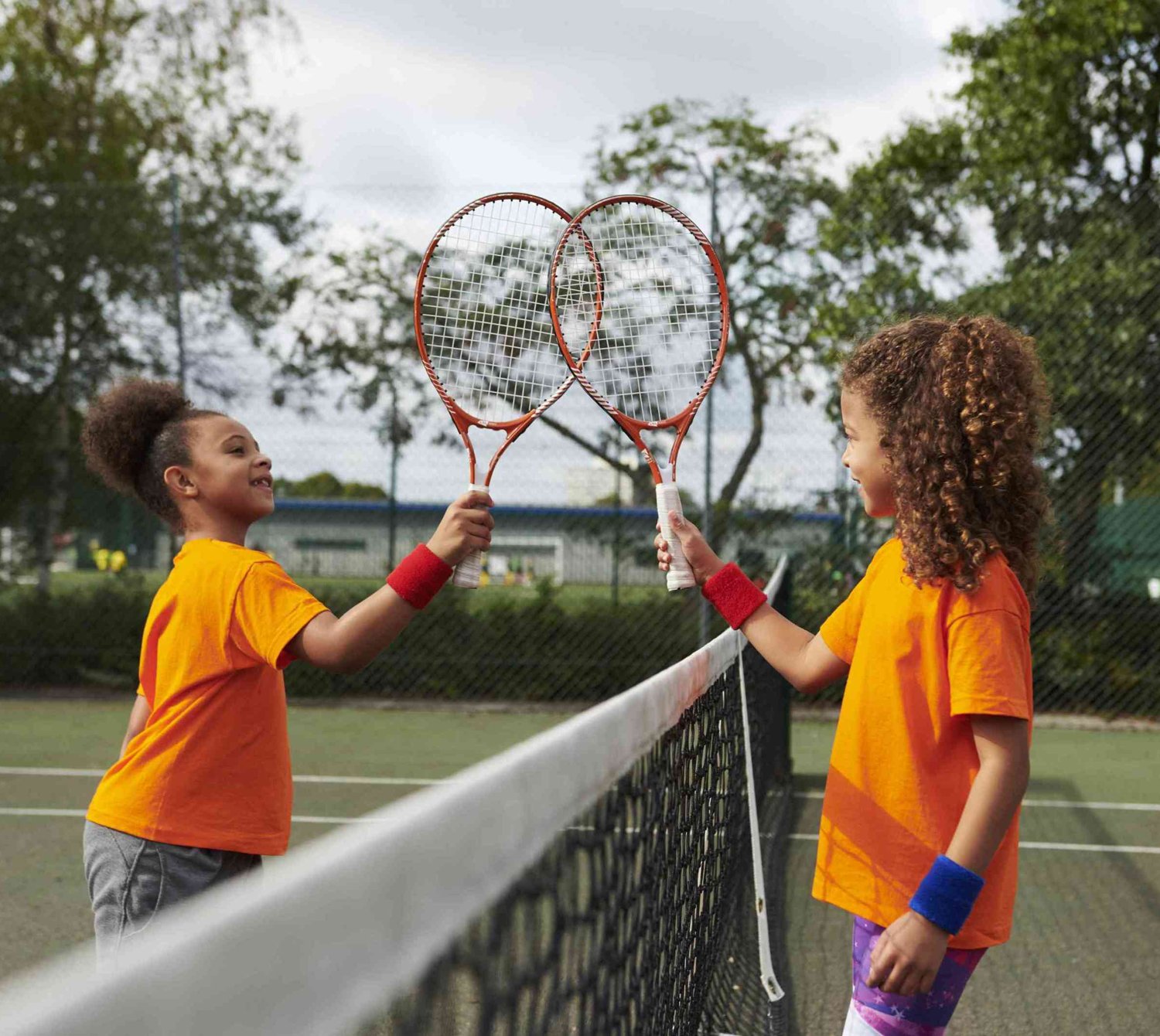 Two young players touching rackets over the net