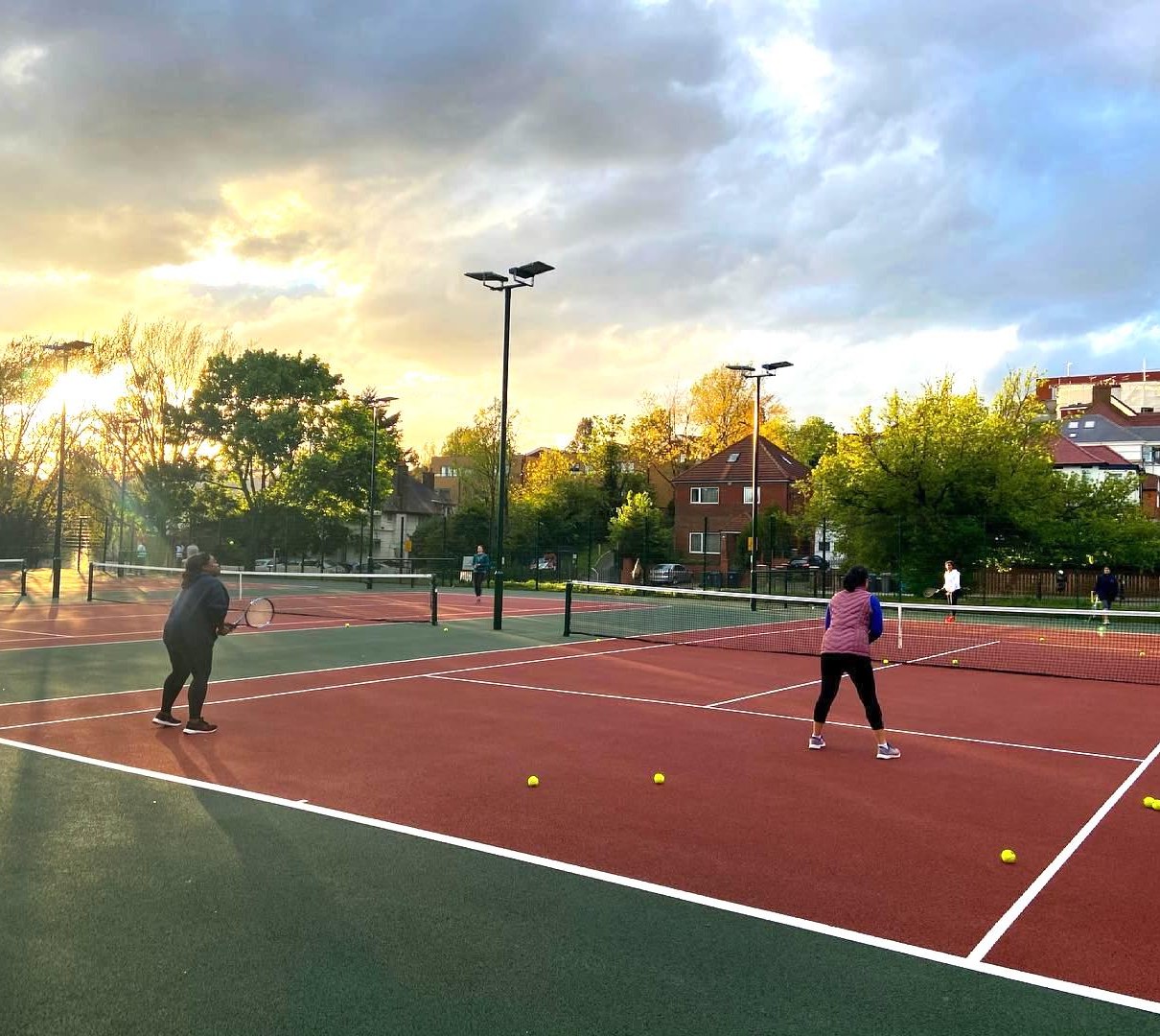Players on a floodlit park court at sunset