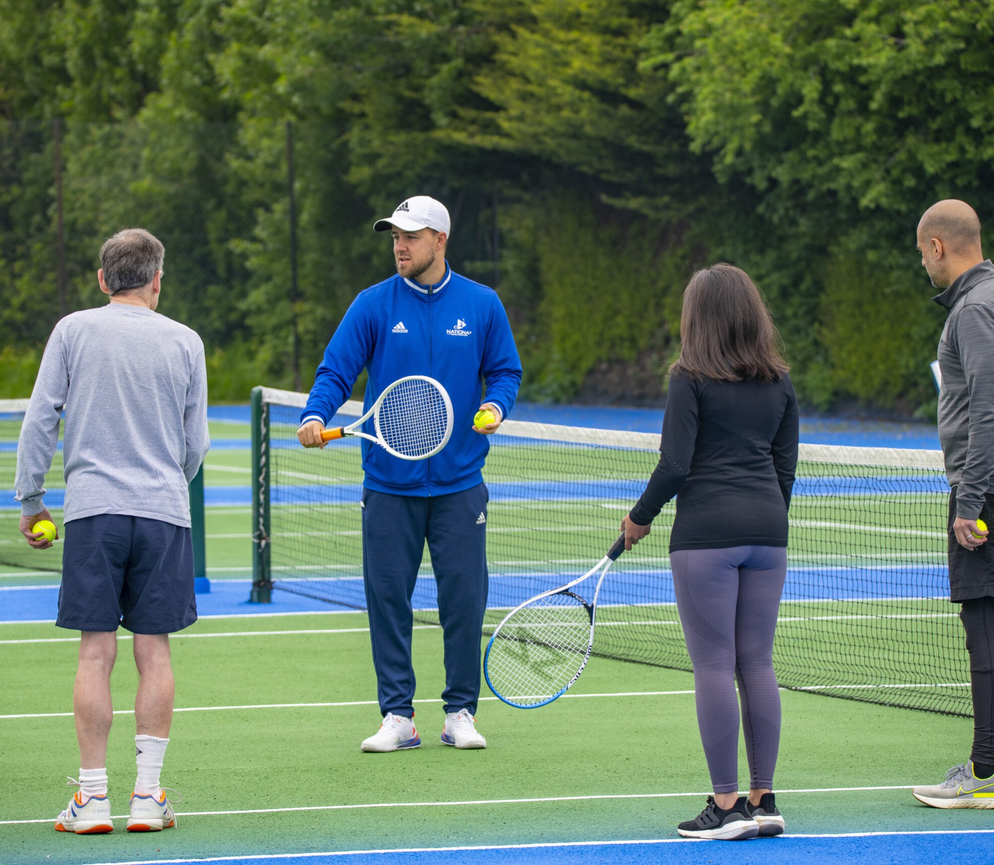 A National Tennis coach with a group of players at the net