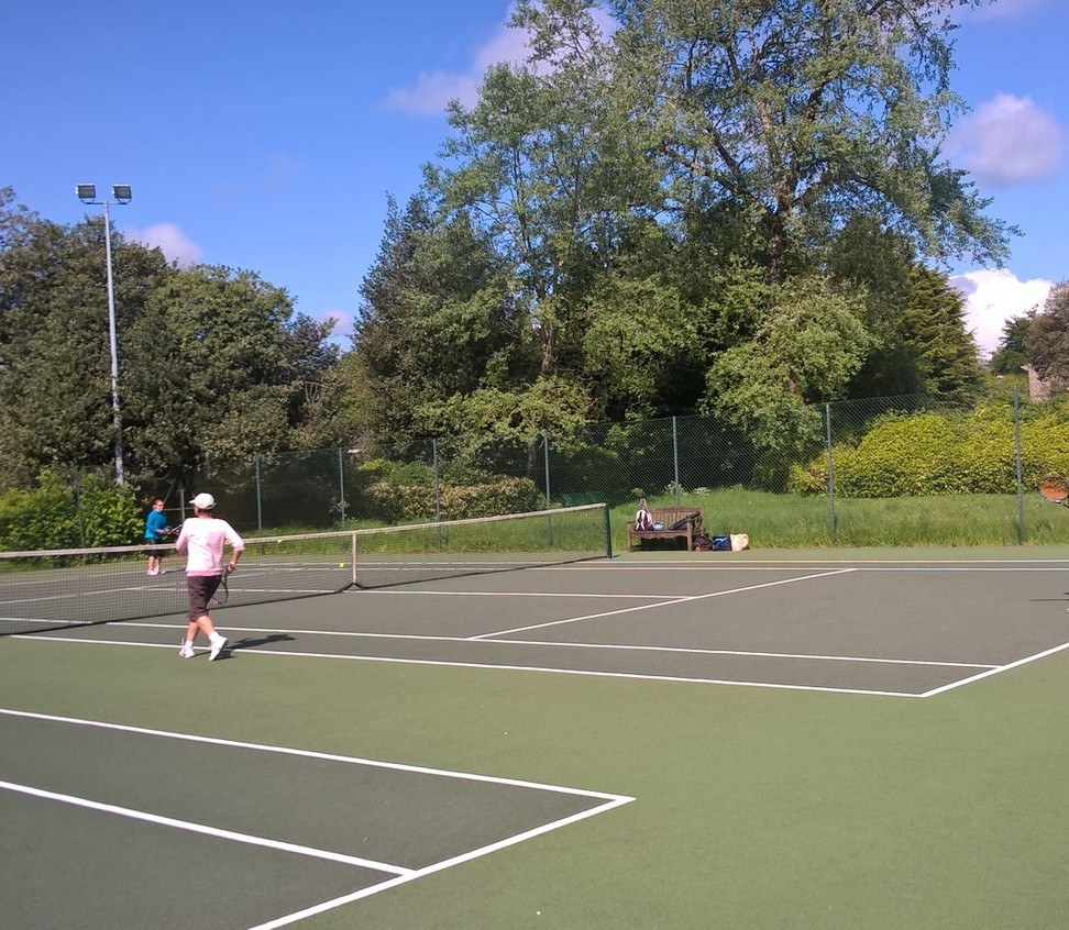 People playing on park tennis courts on a sunny day