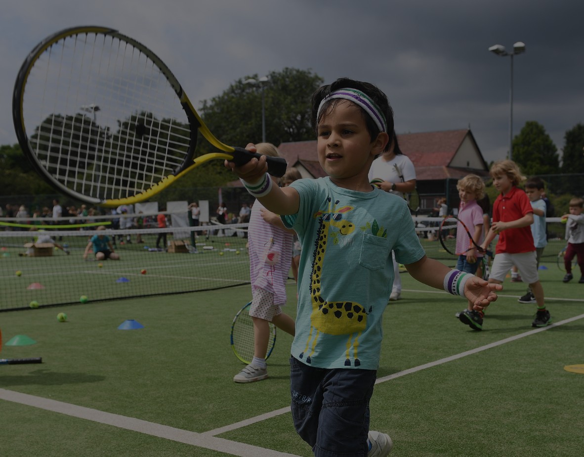 Children playing tennis at a busy community open day