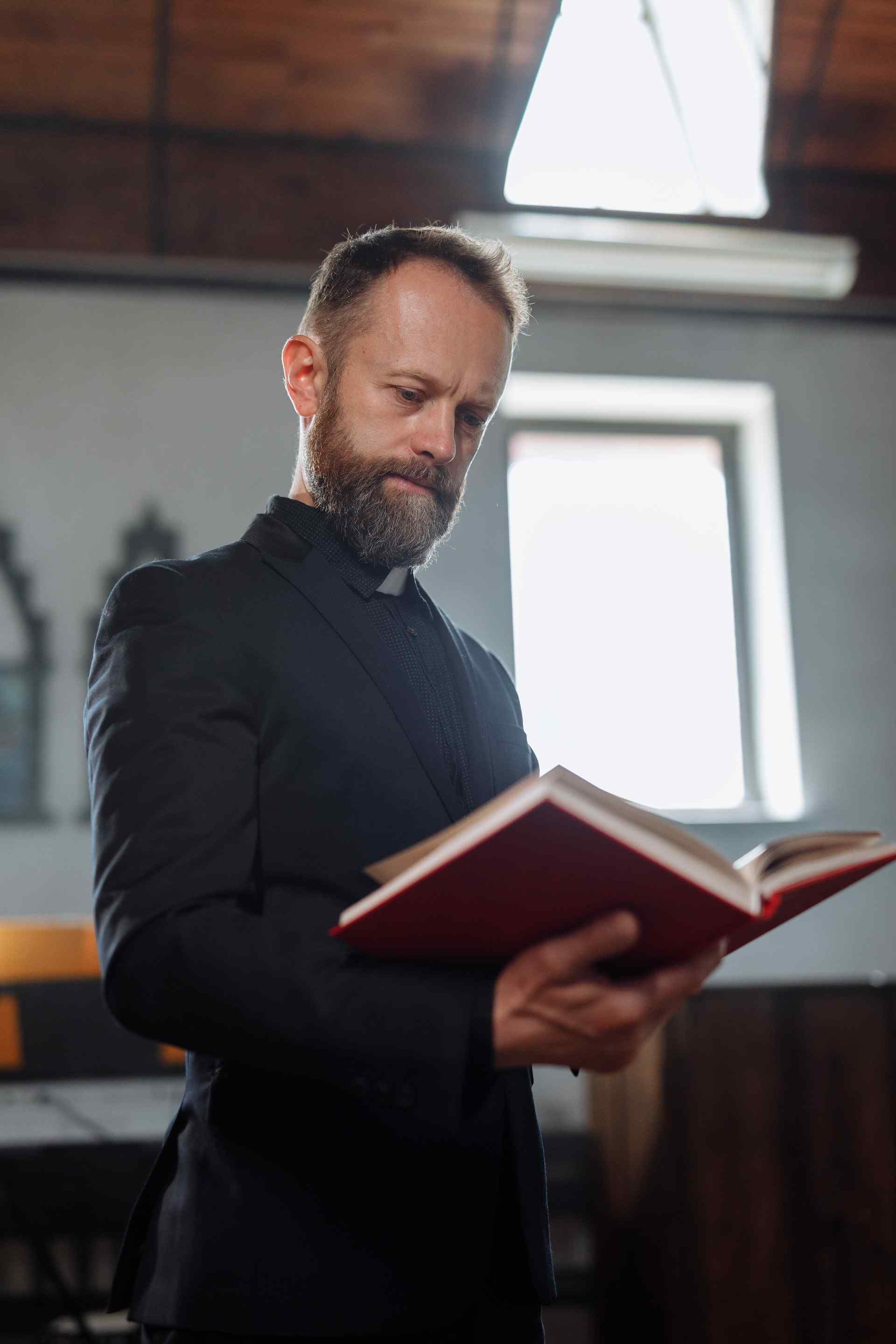 A bearded man in formal attire, immersed in reading a book.