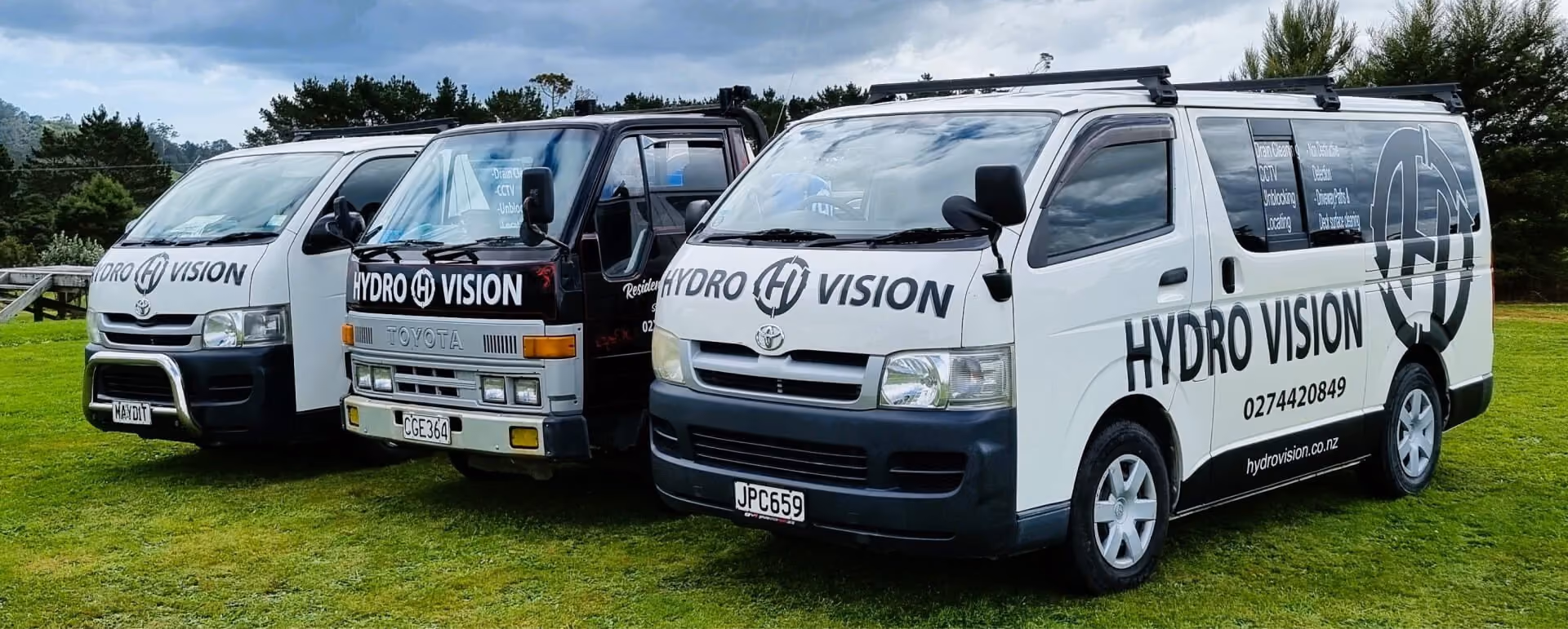 Three Hydro Vision drainage service vehicles parked on grass
