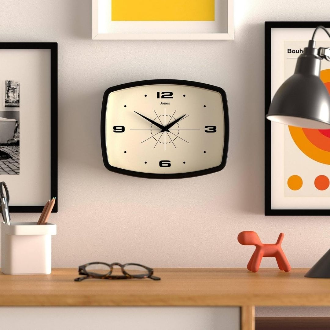 A retro TV-shaped wall clock with an analog display and a matte finish, mounted on a wall in a modern interior.