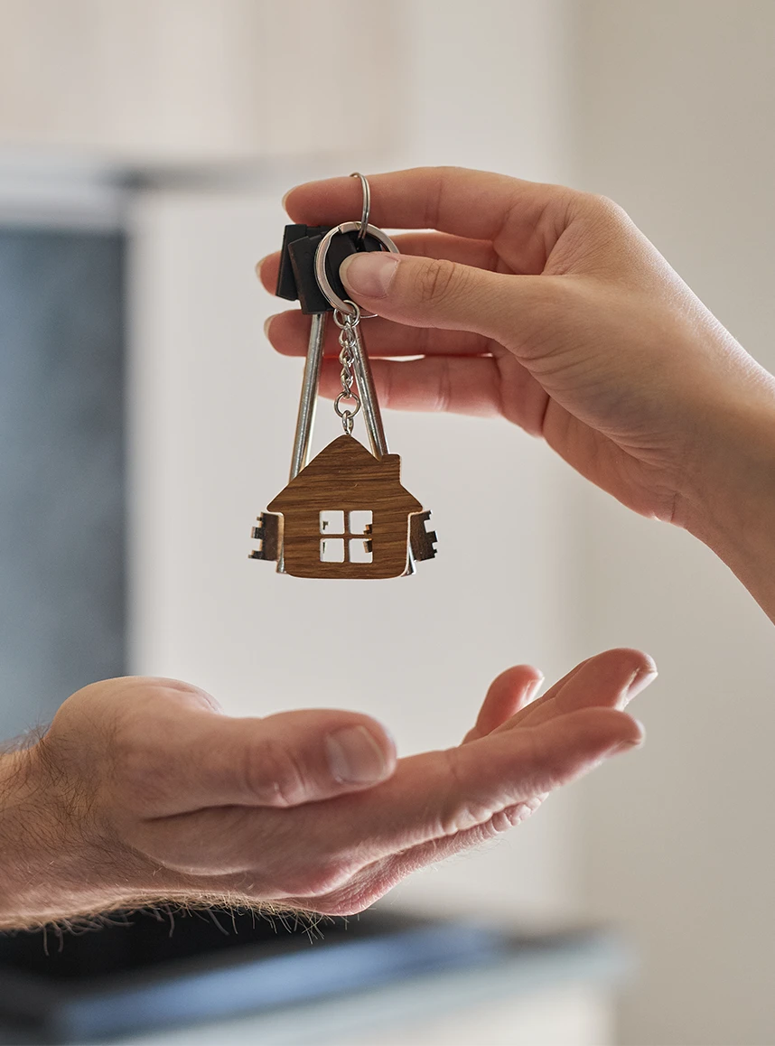 Hand holding a keyring with house-shaped keychains above an open hand.