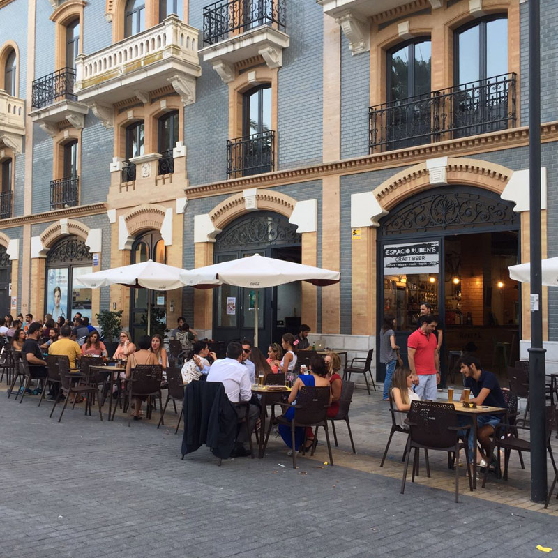 Personas sentadas en mesas al aire libre frente en la terraza del Espacio Rubens
