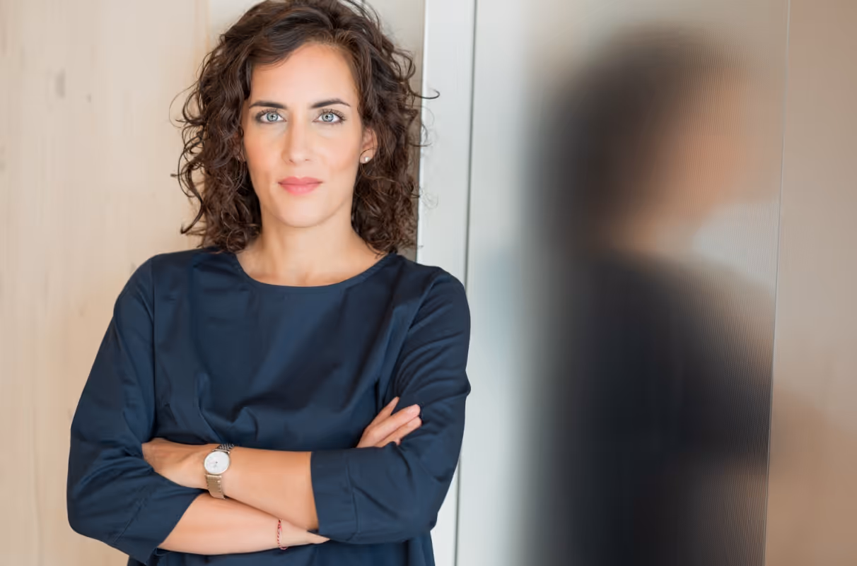 Elif Mucan in dunkelblauem T-SHirt mit verschränkten Armen und einem Lächeln