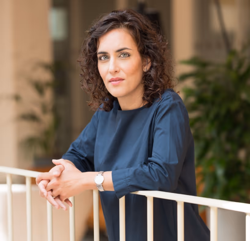 Elif Mucan im blauen Shirt lehnt über ein weißes Geländer