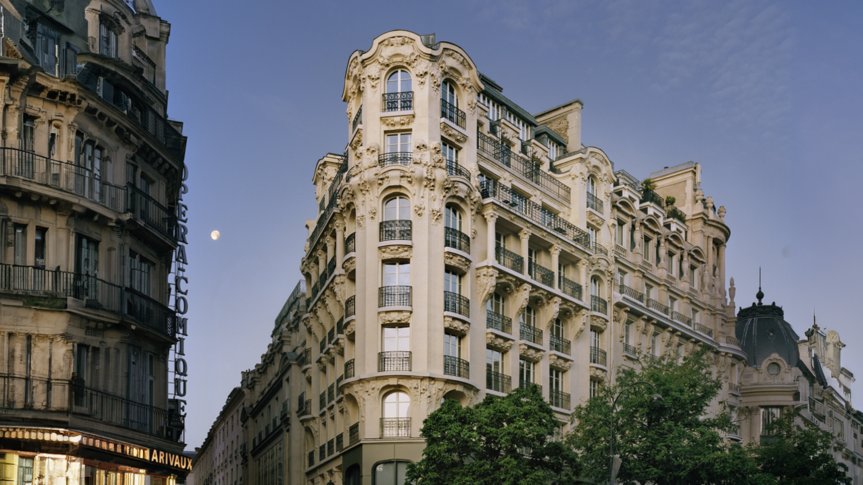 Ornate historic Parisian buildings with wrought iron balconies against a blue sky at dusk.