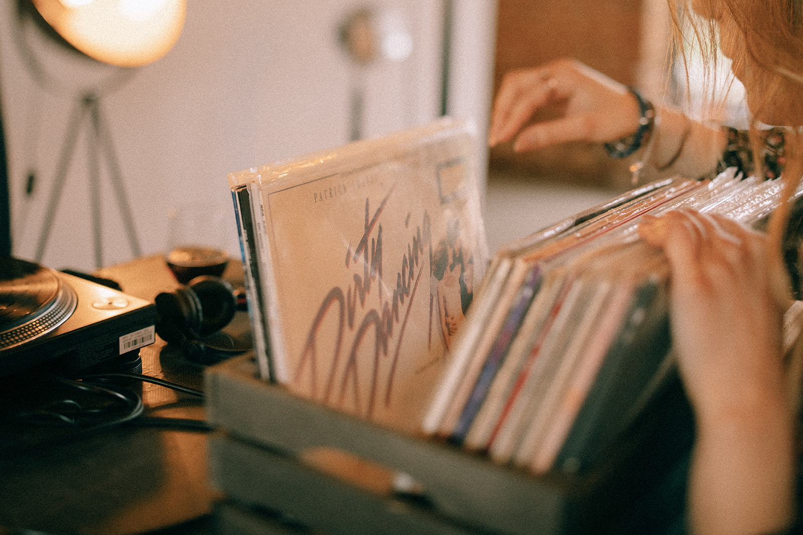 Osoba przegląda płyty winylowe przy gramofonie; na froncie okładka soundtracku „Dirty Dancing”.