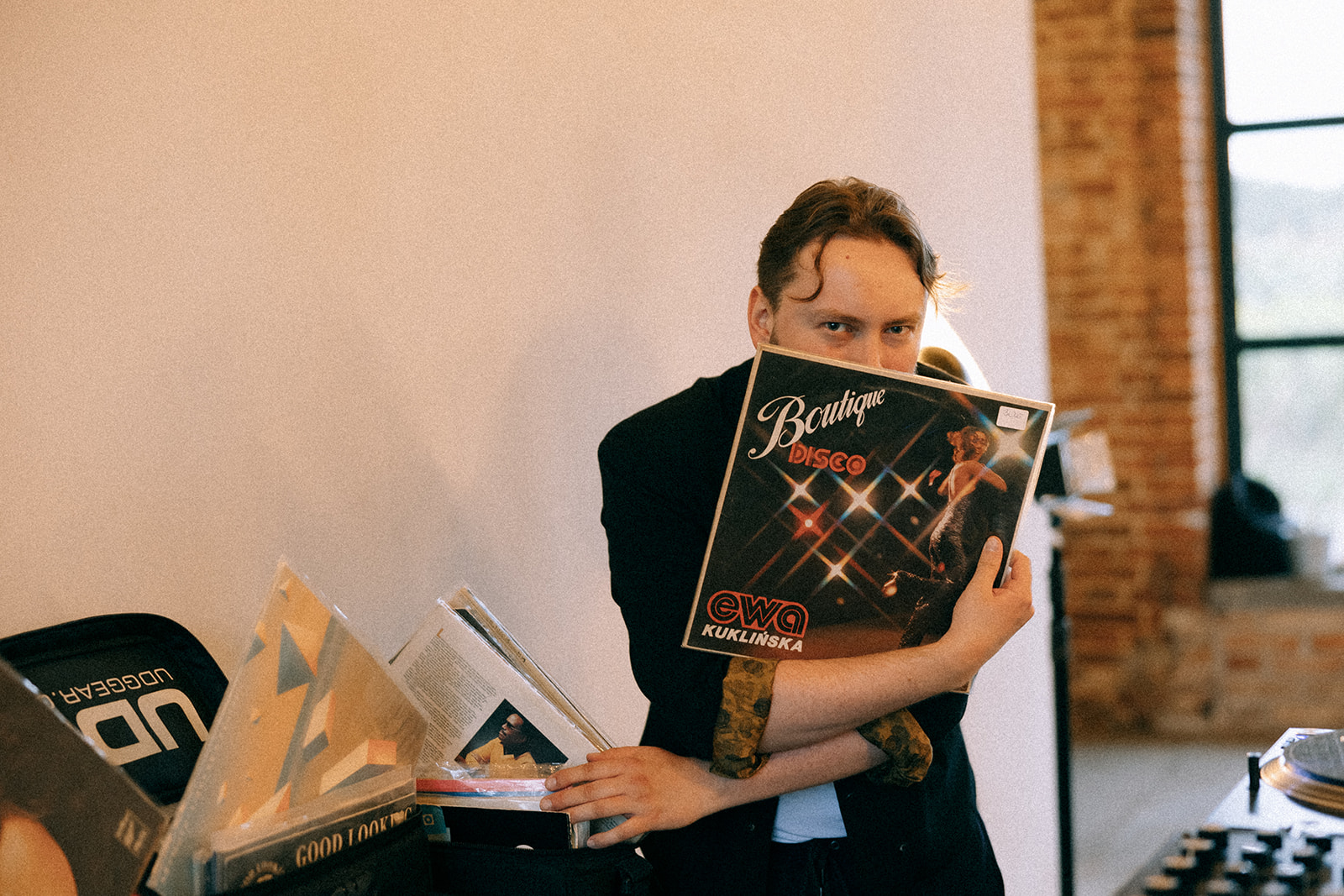 DJ pozuje z winylem „Boutique Disco – Ewa Kuklińska”, zasłaniając nim częściowo twarz.