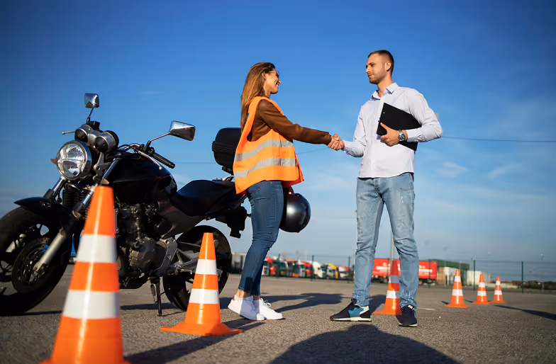 Motorradfahrschülerin schüttelt die Hand vom Fahrprüfer