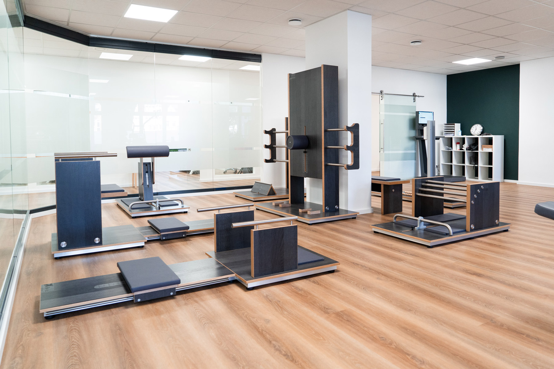 Moderner Trainingsraum mit mehreren Geräten zur funktionellen Bewegung und Rehabilitation auf hellem Holzboden.