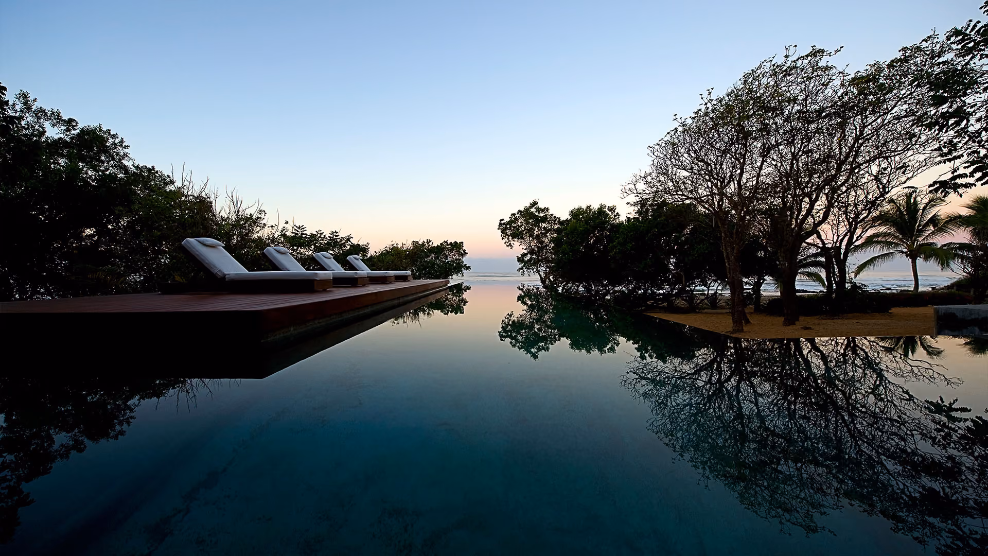 Infinity-edge lap pool at dawn above the Pacific