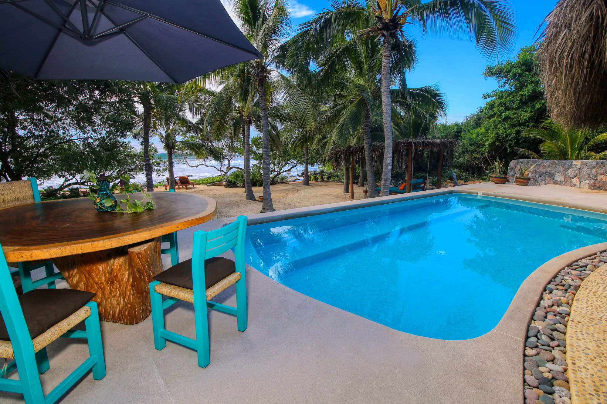 Pool, palms and beach at Villa Armonia
