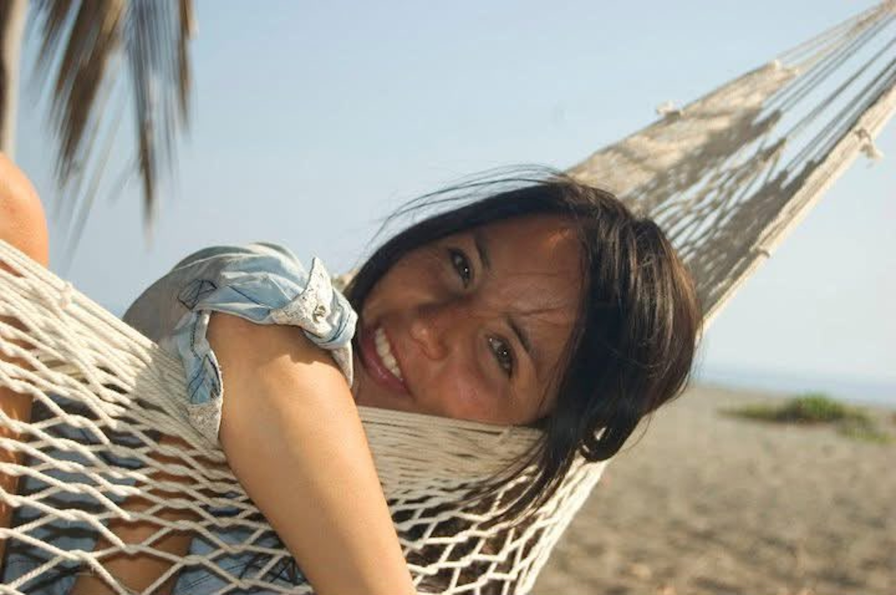 Maria Fernanda smiling in a hammock on the beach in 2010