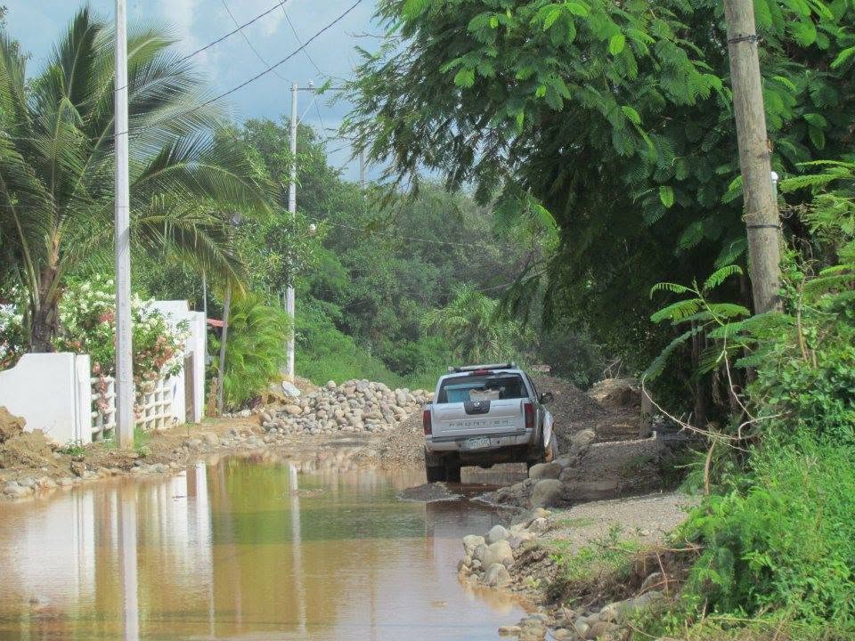 A pickup truck stuck in a flooded, muddy road during paving