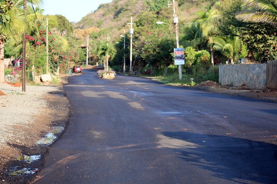 Fresh black asphalt with a planted island in the middle of the road