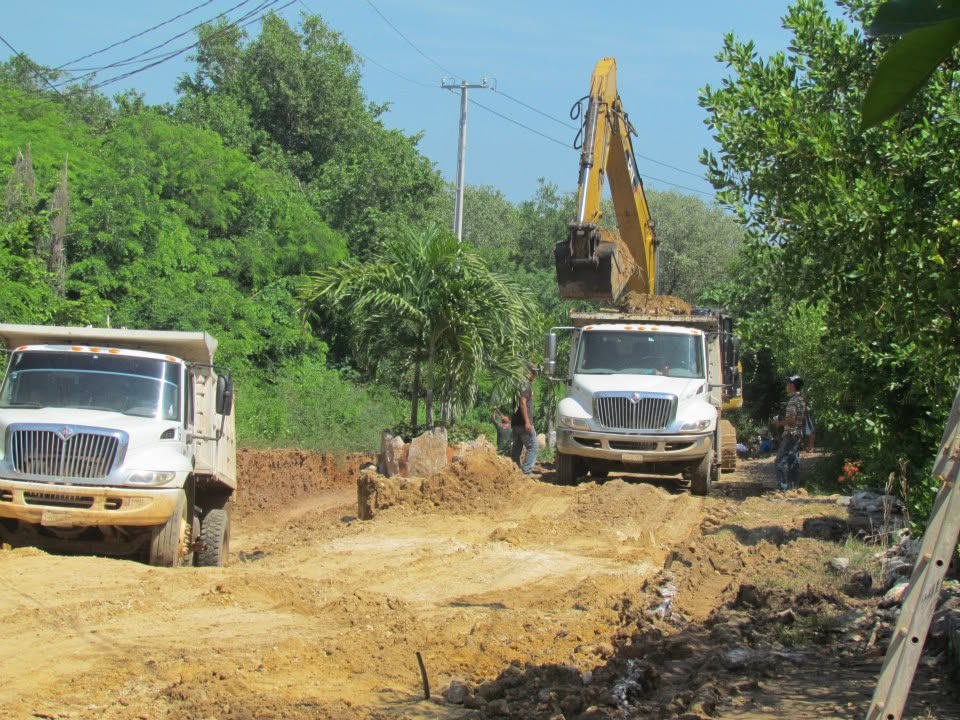 An excavator loading dump trucks on the dirt road during the first phase of work