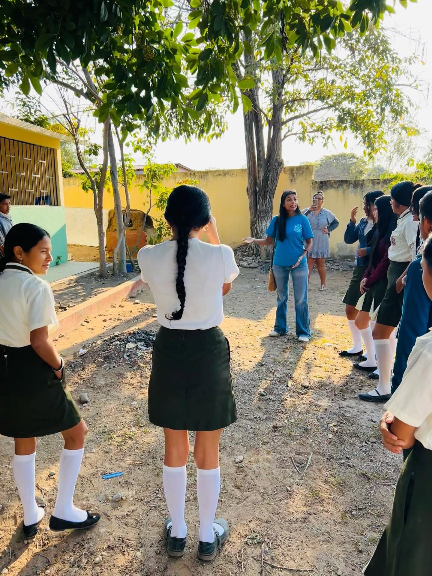 A Proyecto Saladita educator speaking with a group of students in a schoolyard