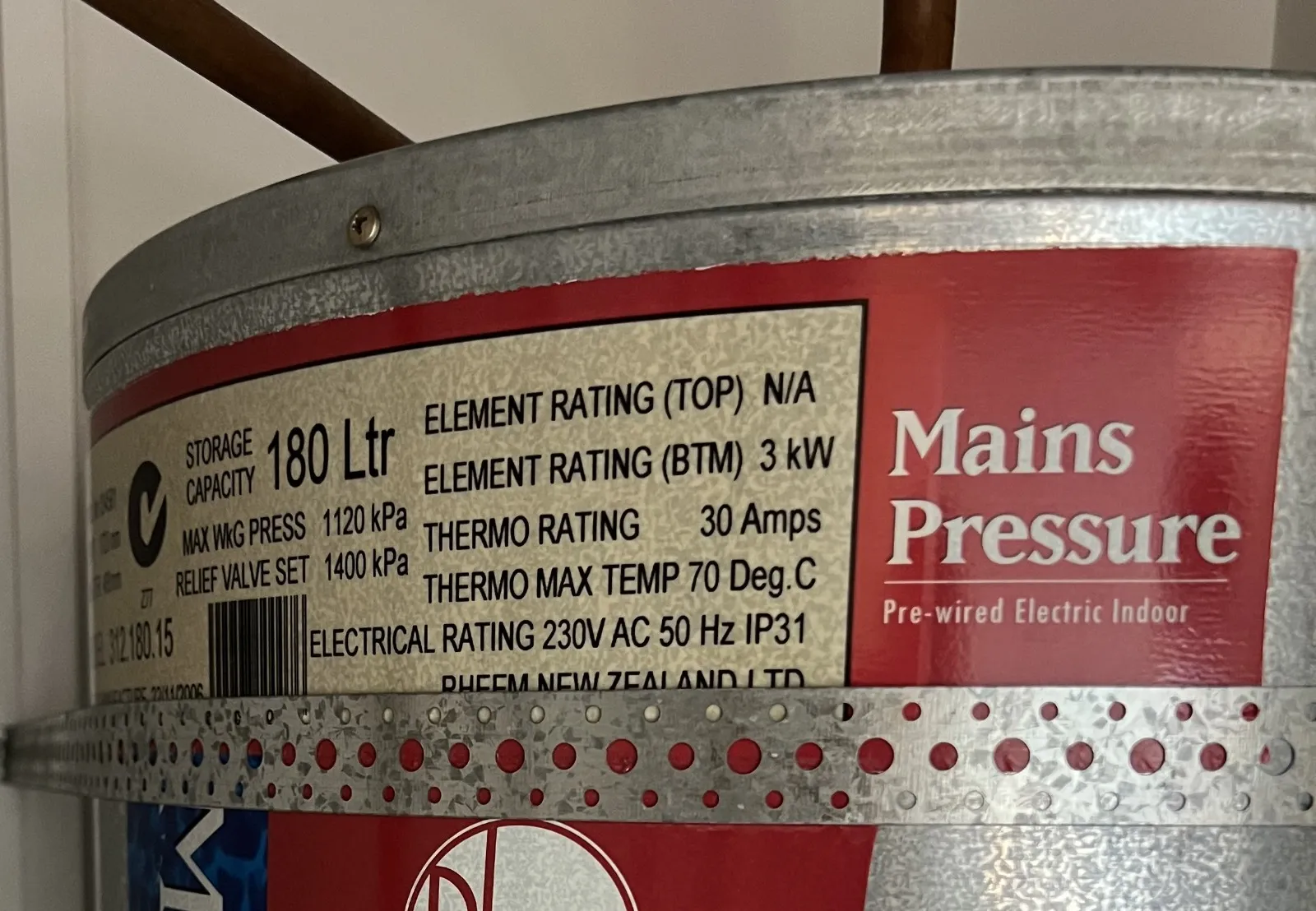 Label on a water heater showing 180 L storage, 1120 kPa max pressure, and 3 kW bottom element rating.