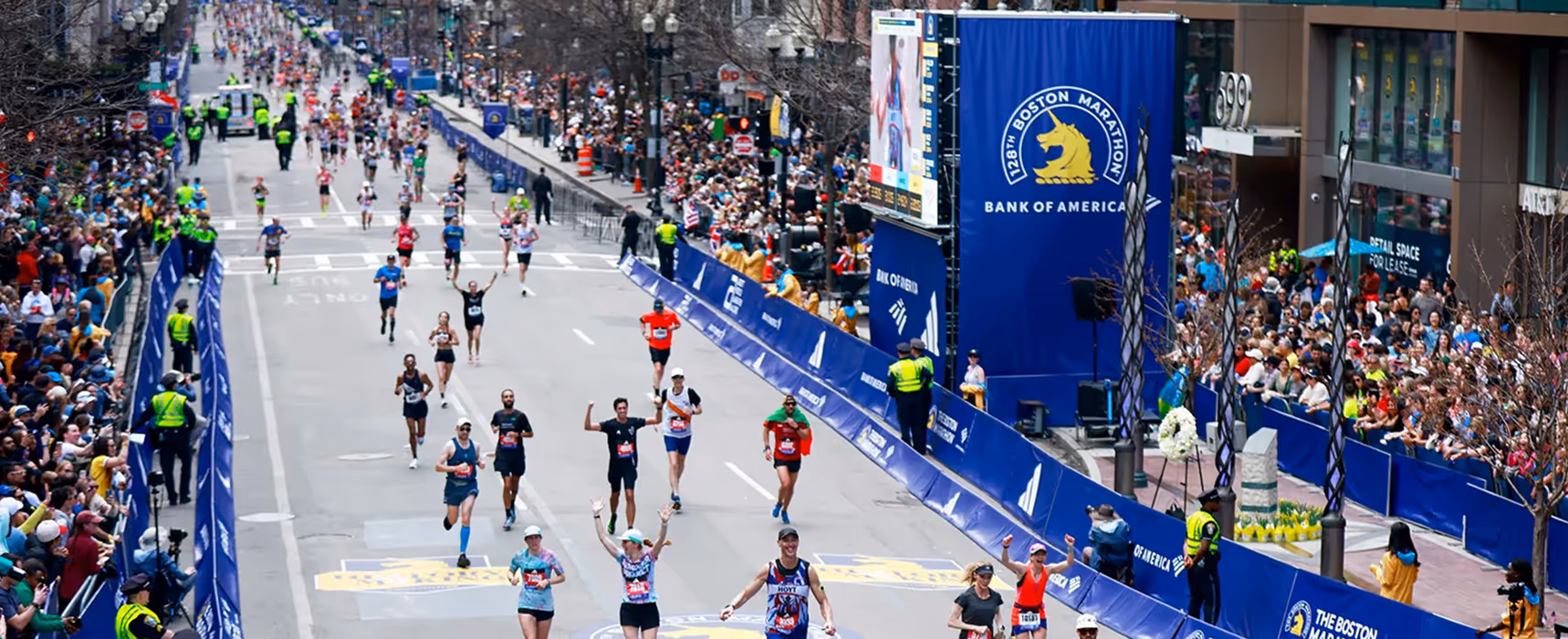 Runners approaching the finish line at the Boston Marathon as crowds cheer along the course.