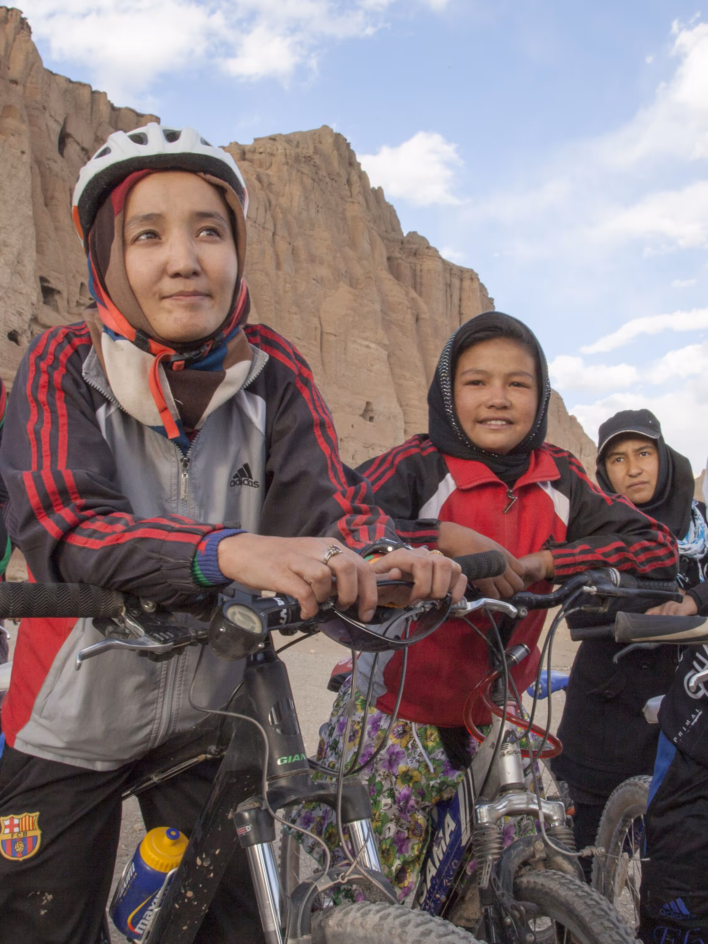 Afghan girls with bicycles featured in The Alchemists, highlighting women’s cycling in Afghanistan.