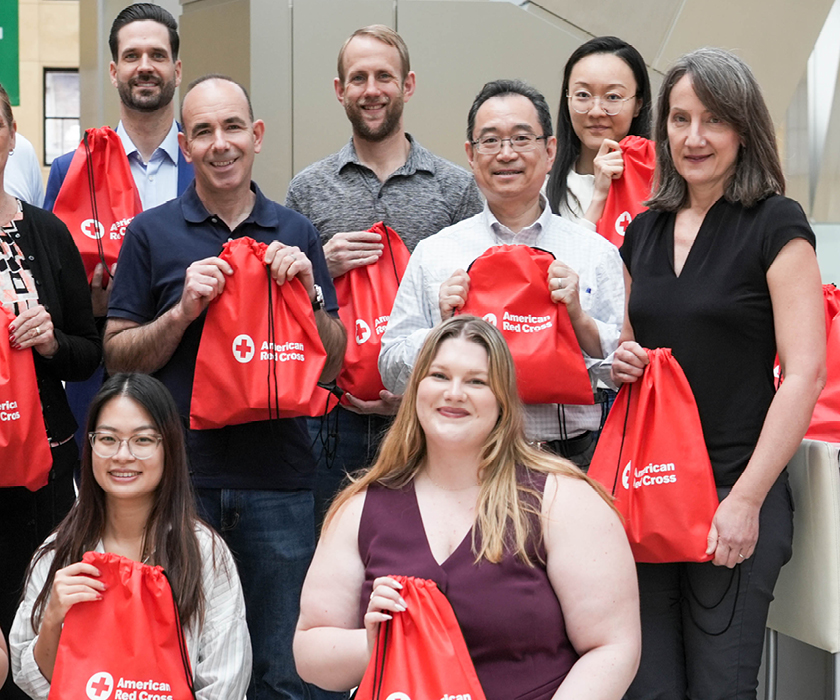 Hearst employee holding American Red Cross bags as part of a corporate donation initiative.