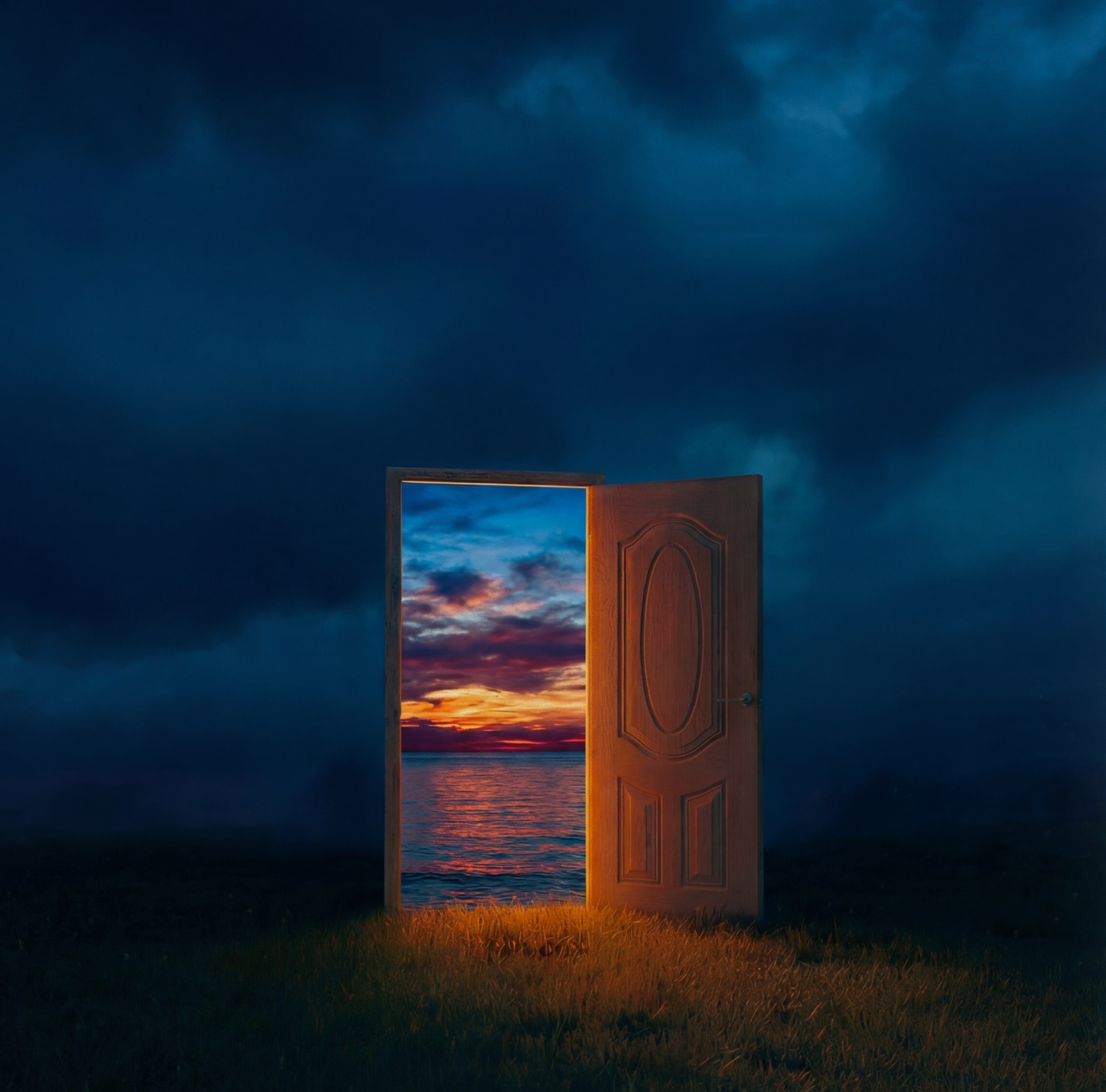 Wooden door standing open on grass at night, revealing a vibrant sunset over the ocean.