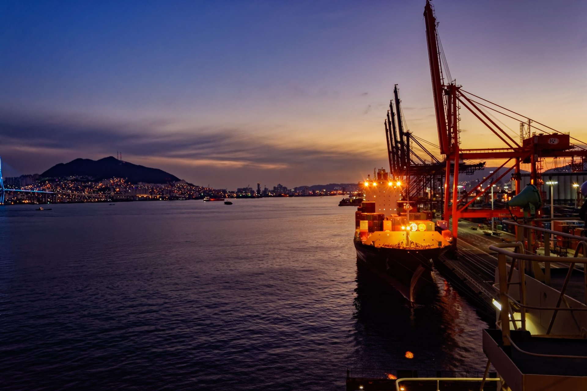 Container ship at berth under gantry cranes at the Port of Busan at night