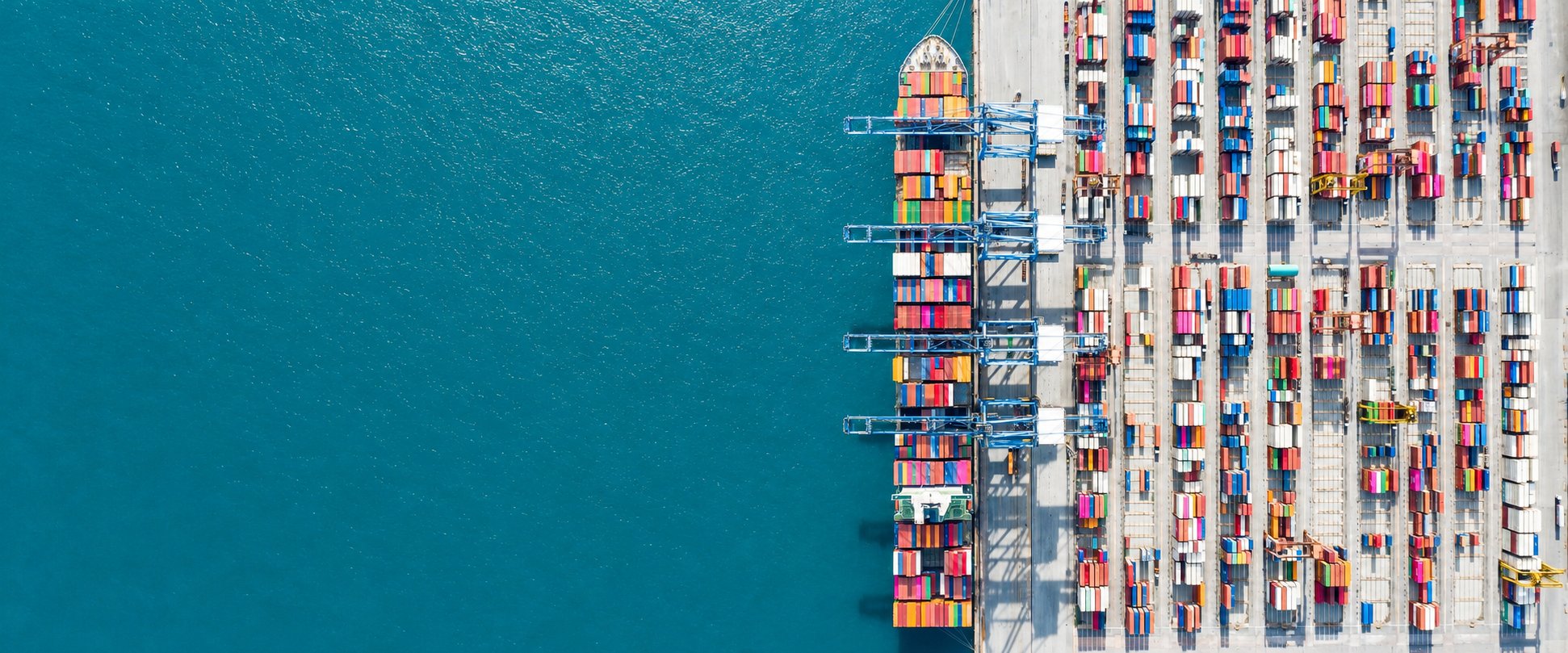 Aerial view of a container ship berthed at a port terminal beside stacked shipping containers, import cargo cleared through customs and coordinated by AEEM Shipping