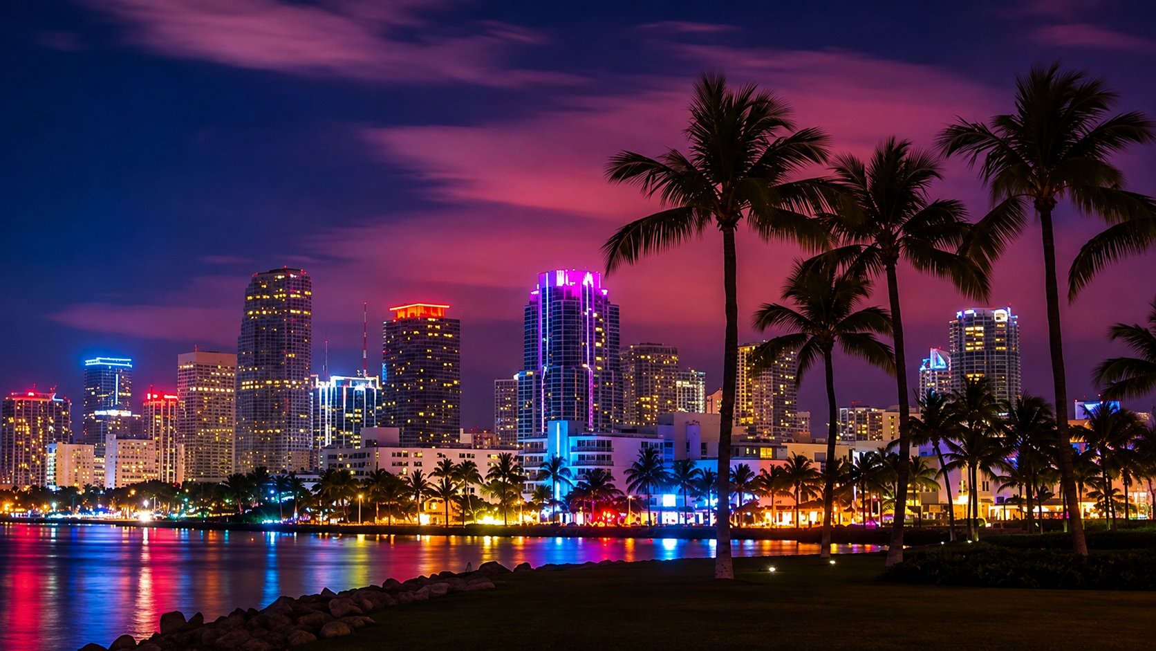 Miami skyline lit in neon at dusk across Biscayne Bay with palm trees along the waterfront, Florida