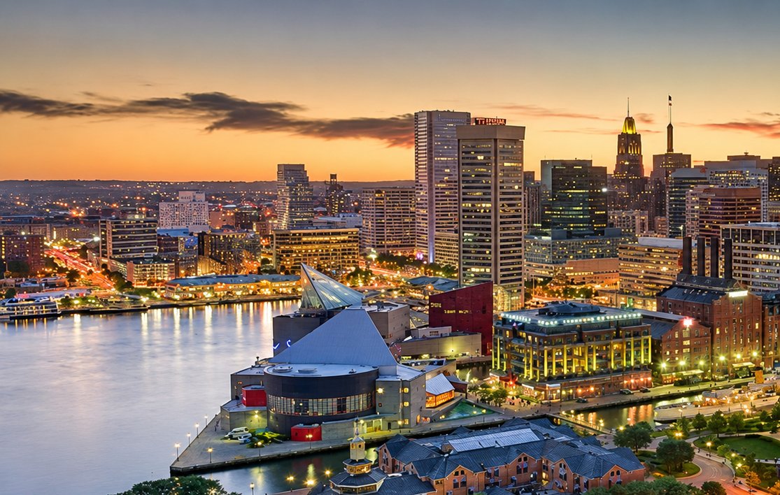 Baltimore Inner Harbor at dusk with the aquarium and downtown skyline lit along the waterfront, Maryland