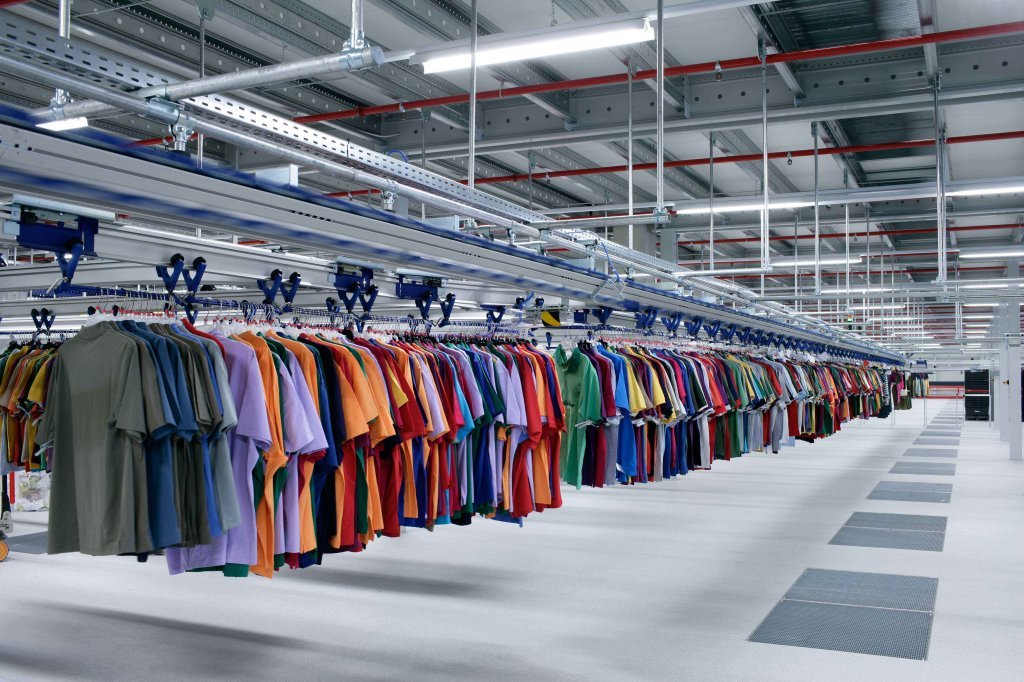 Colorful shirts hanging on an overhead garment rail conveyor system inside an apparel distribution center