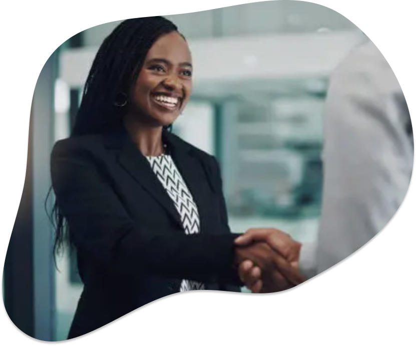 Smiling woman in business attire shaking hands with another person in an office setting.