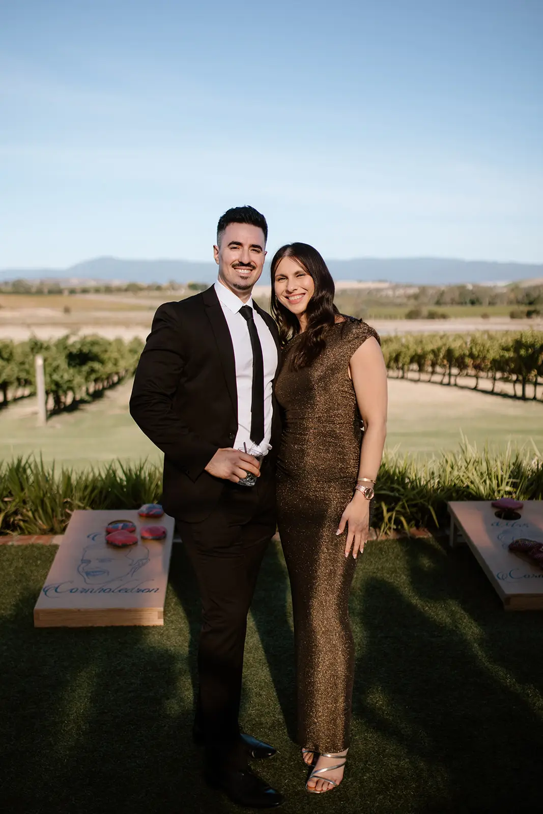 A woman in a sage green silk slip dress giving a speech at a wedding reception, wearing black multi-strap dressy sandals with a low block heel on a concrete floor.